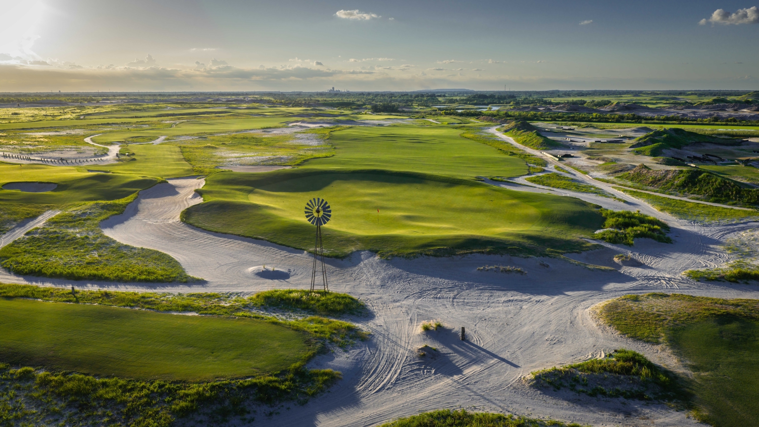 The 9th hole of Streamsong Black golf course, with a large windmill in the middle of winding sand dune
