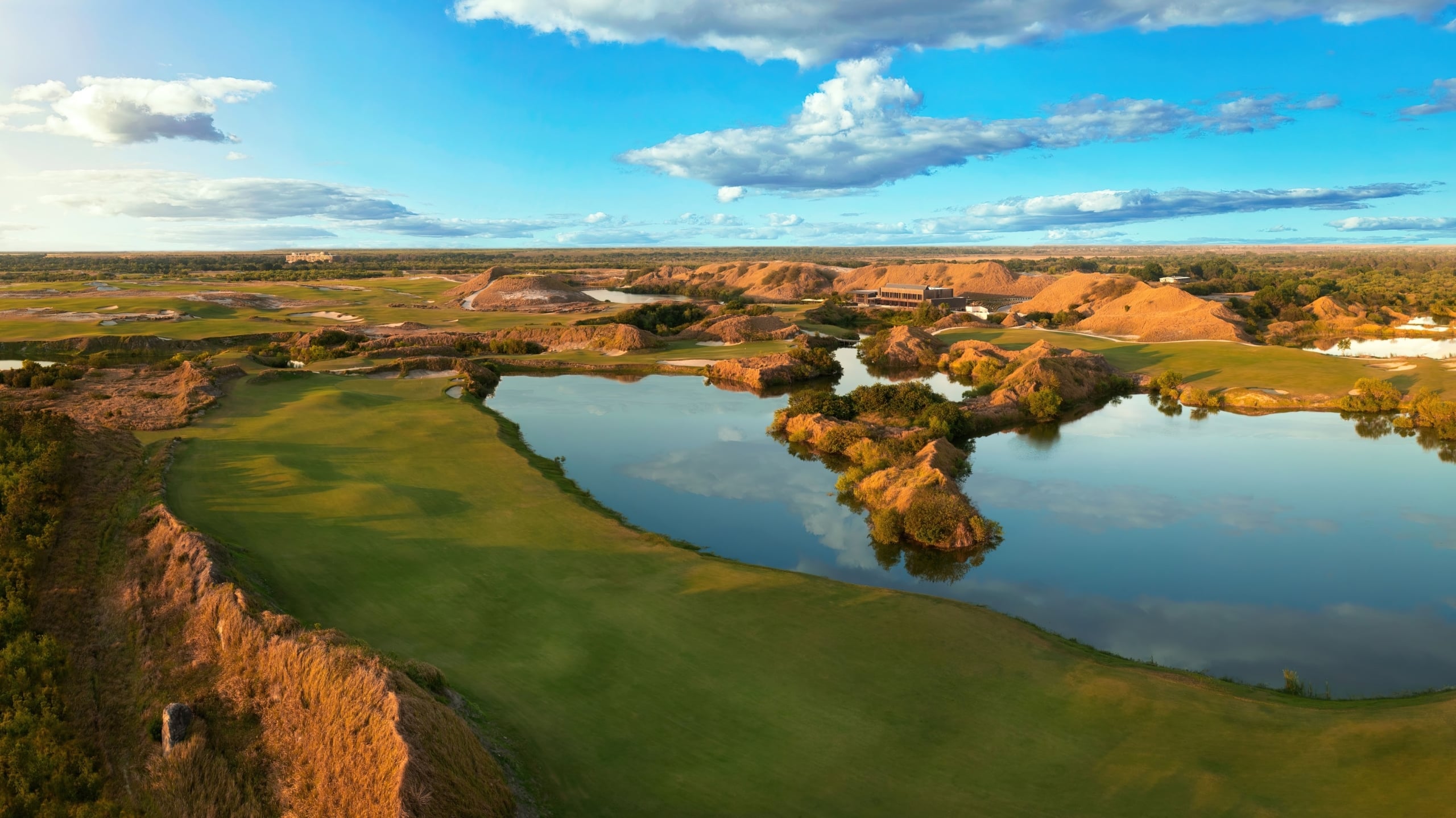 A stretch of fairway on Streamsong Red golf course, with dunes of sand clustered around a water feature