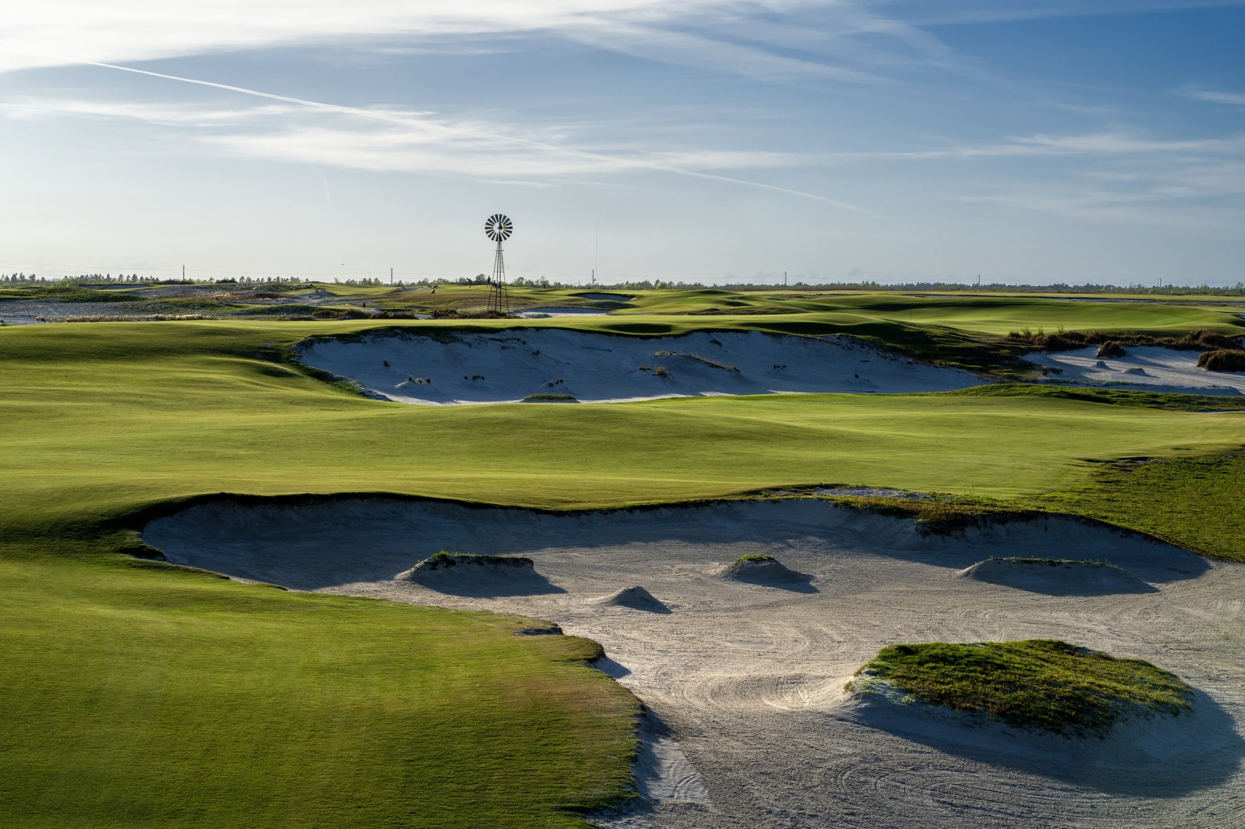 Hole 2 of Streamsong Black golf course, with a windmill in the distance