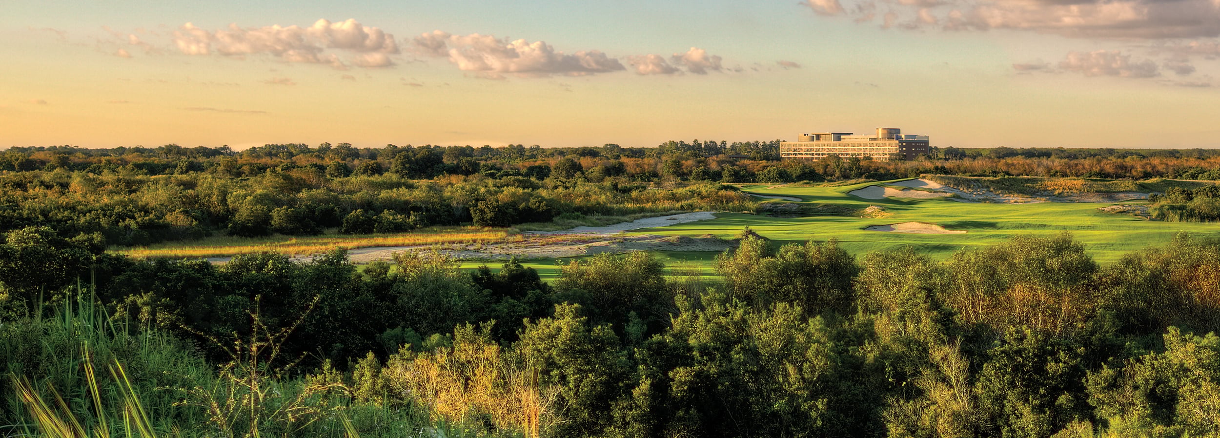 Image of a golf course at sunset with The Lodge in the background