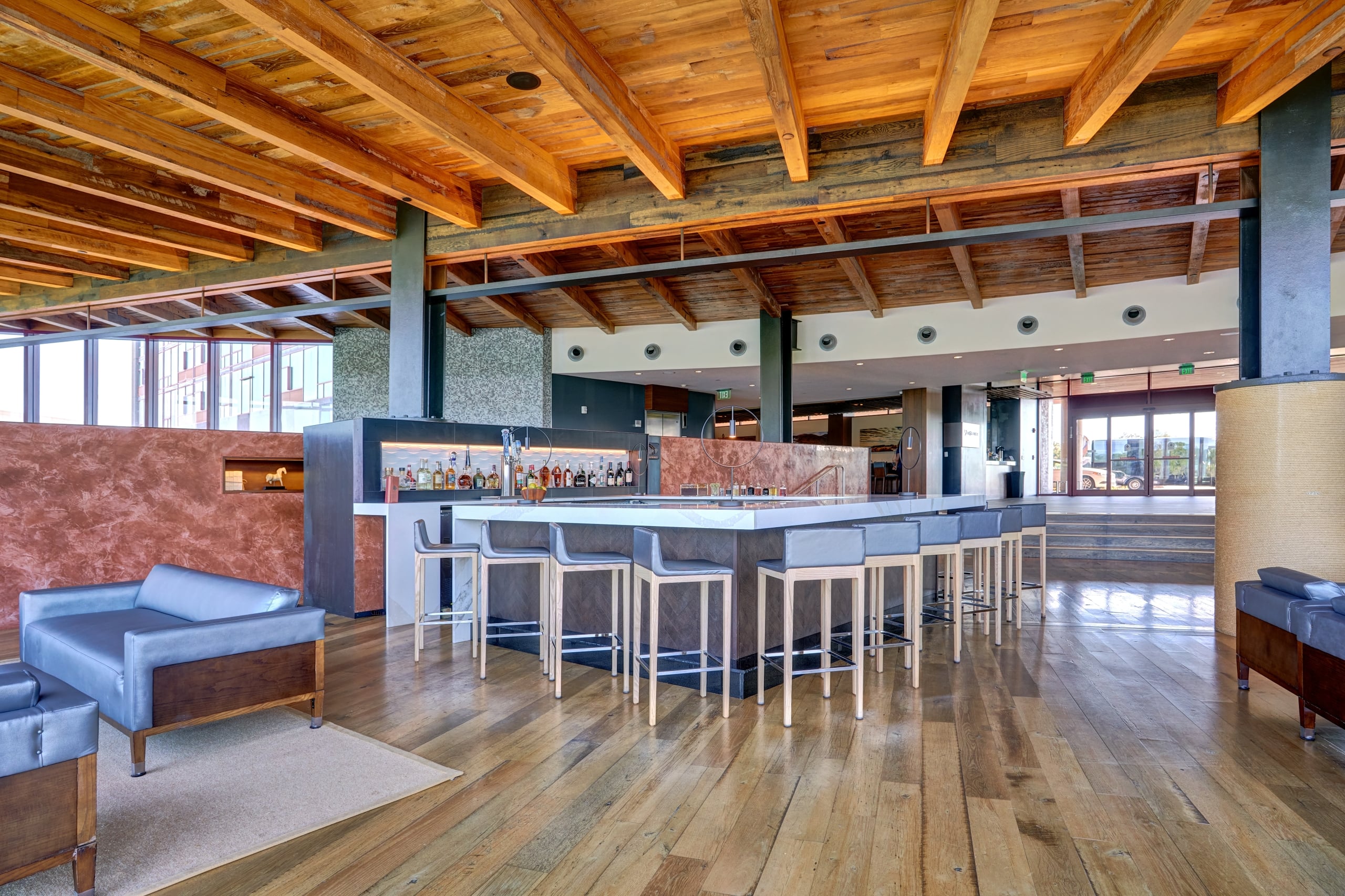 Sleek bar at Streamsong’s Leaf Lounge with modern barstools, wood flooring, and large windows with natural light.