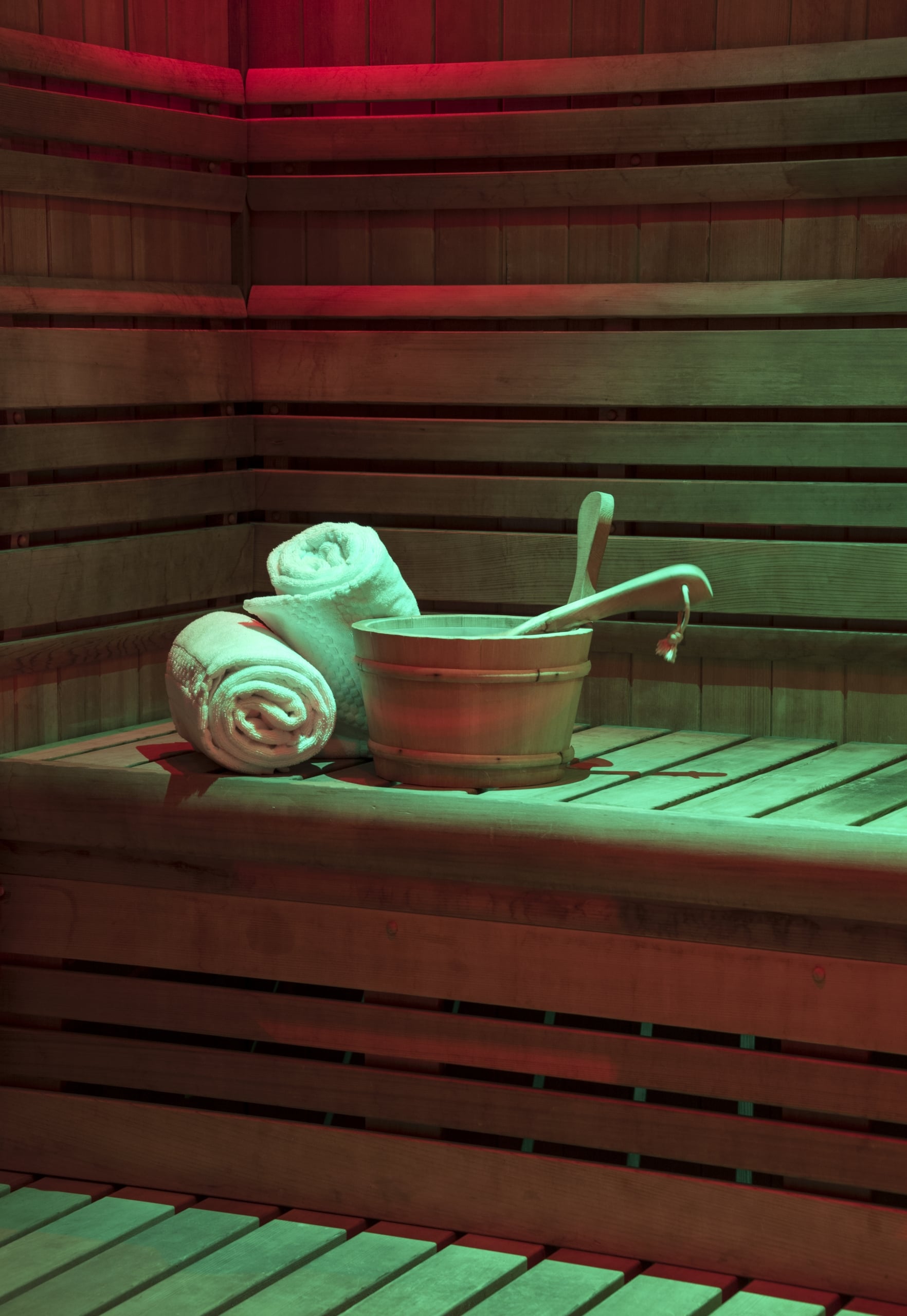 Interior of a cedar wood sauna at Streamsong Spa with rolled white towels and a wooden water bucket with ladles.
