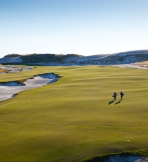 two people walking up the fairway on a sunny day