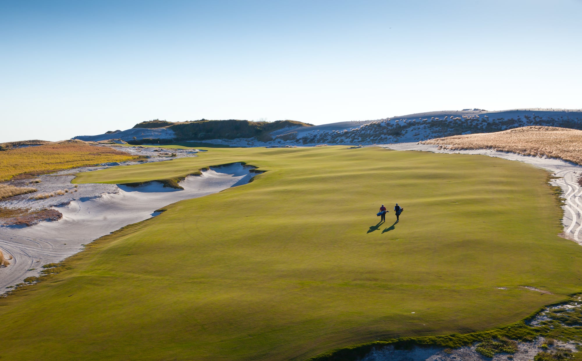 two people walking up the fairway on a sunny day