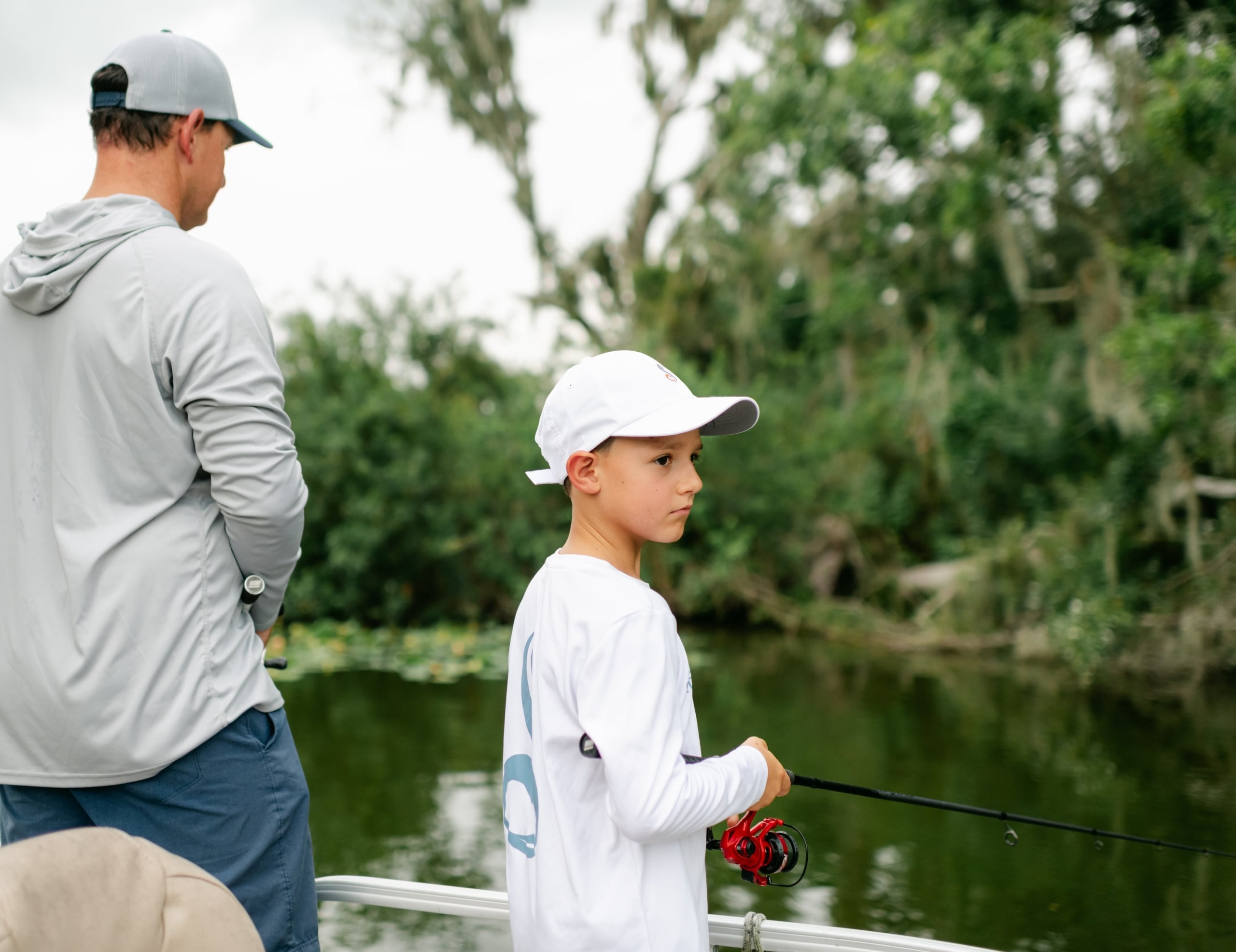 A father and son fishing off a boatThree people fishing on a boat on a guided fishing tour at Streamsong