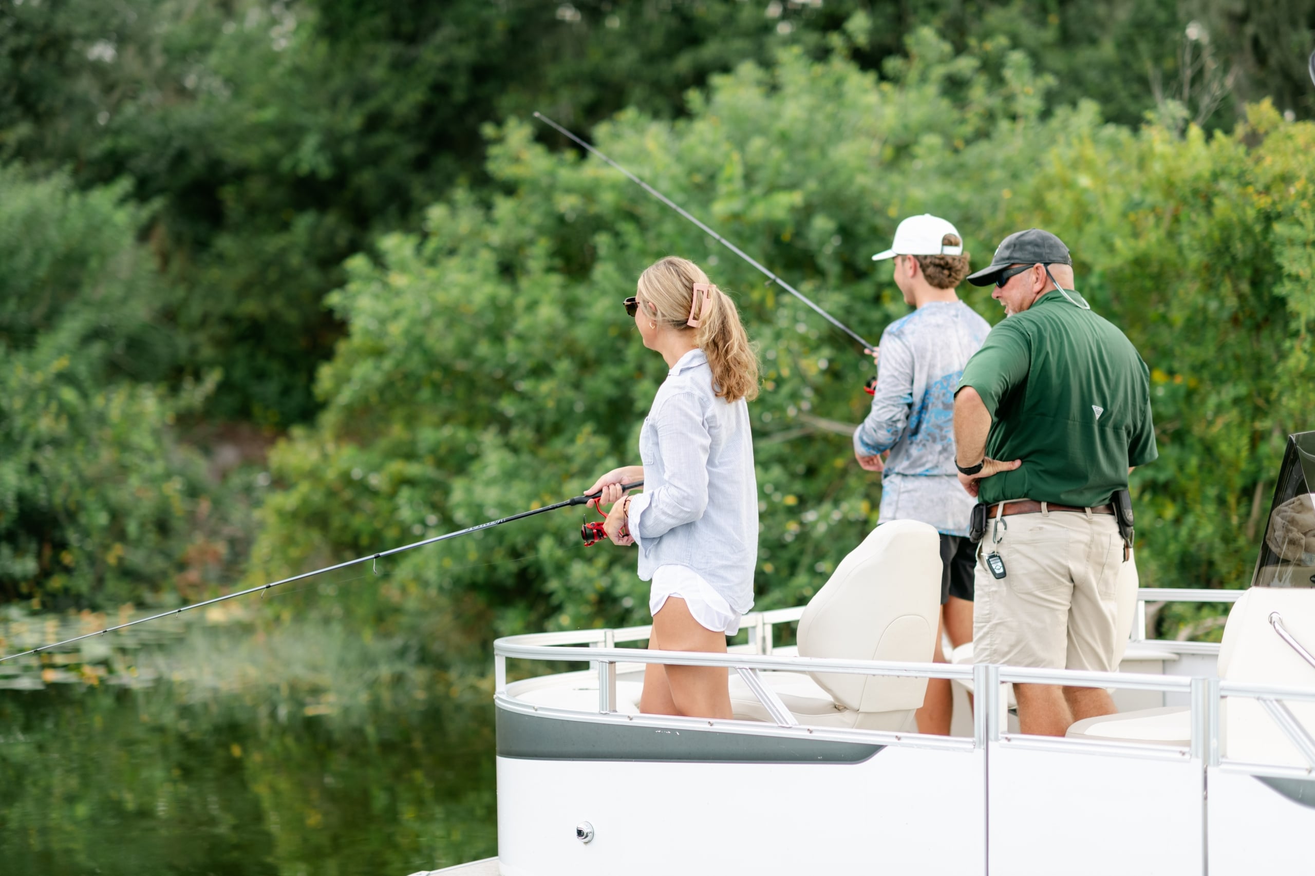 A woman and two men fishing right off the boat Three people fishing on a boaton a guided fishing tour at Streamsong