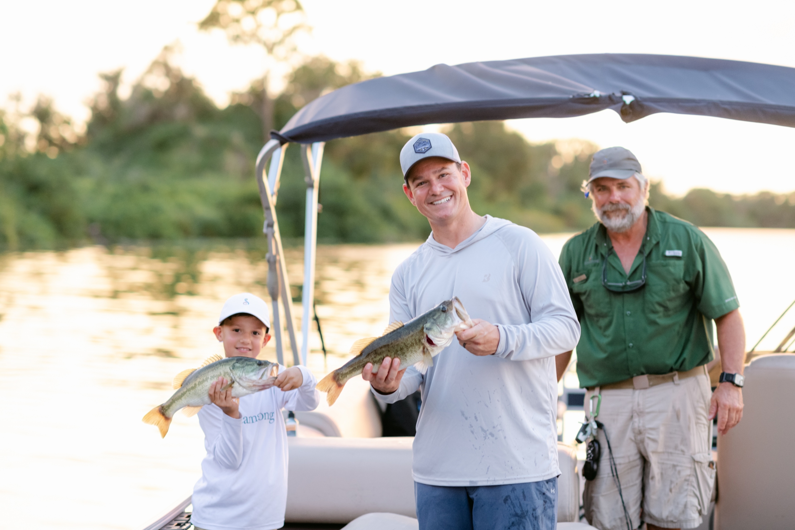 A father and son holding up bass they caught on a guided fishing tour at Streamsong