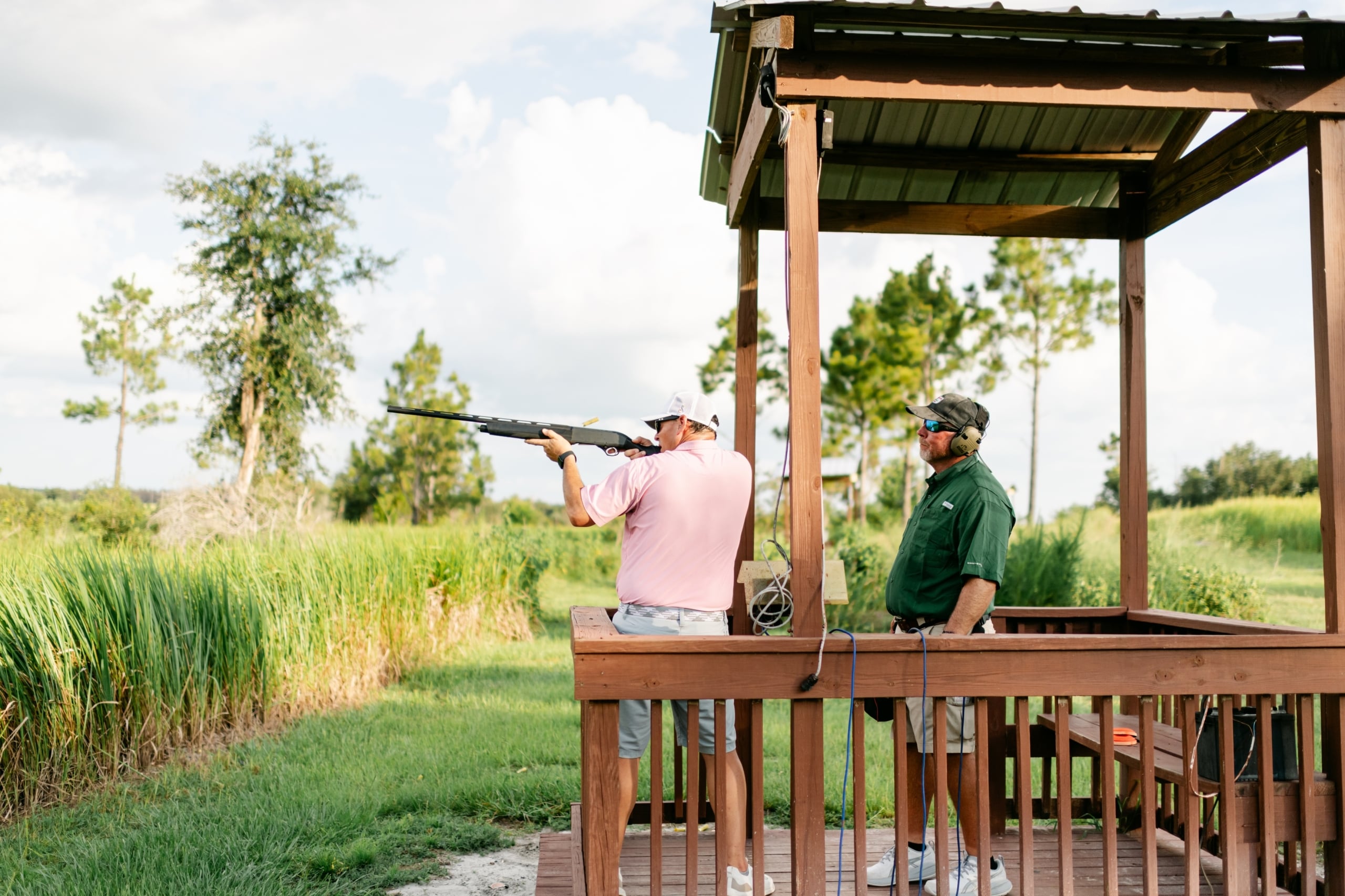 An instructor supervises a man shooting a rifle at a sporting clays demonstration at Streamsong