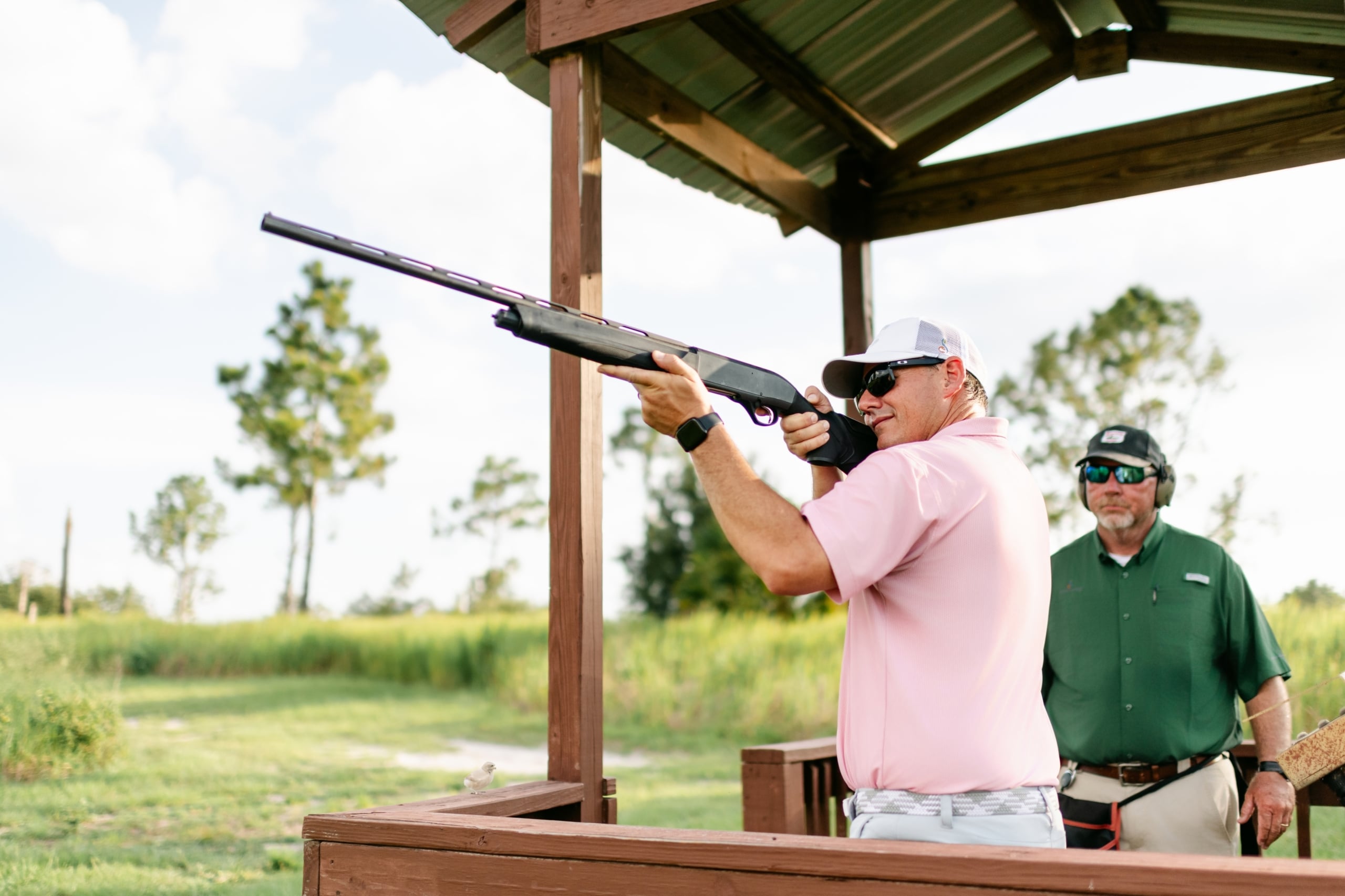 An instructor supervises a man shooting a rifle at a sporting clays demonstration at Streamsong