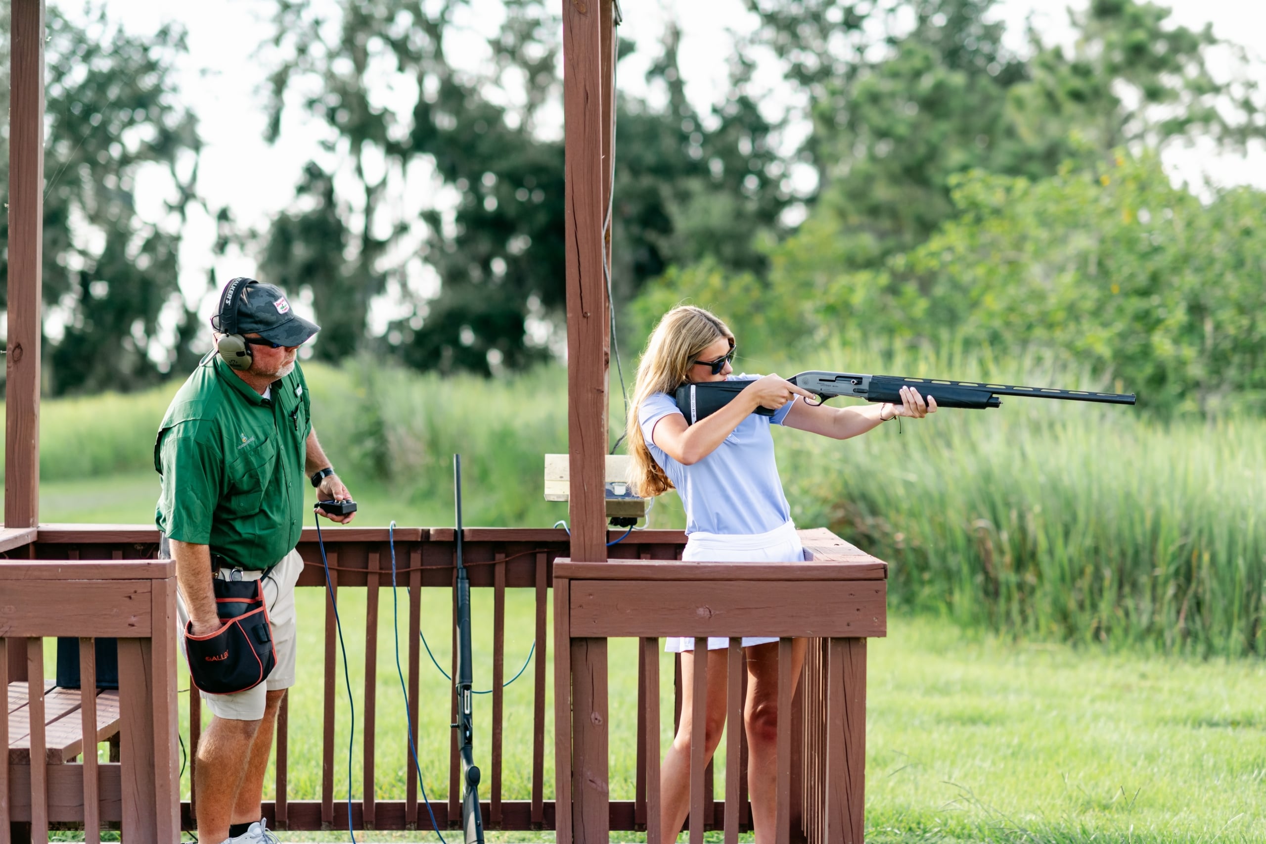 An instructor supervises a woman shooting a rifle at a sporting clays demonstration at Streamsong