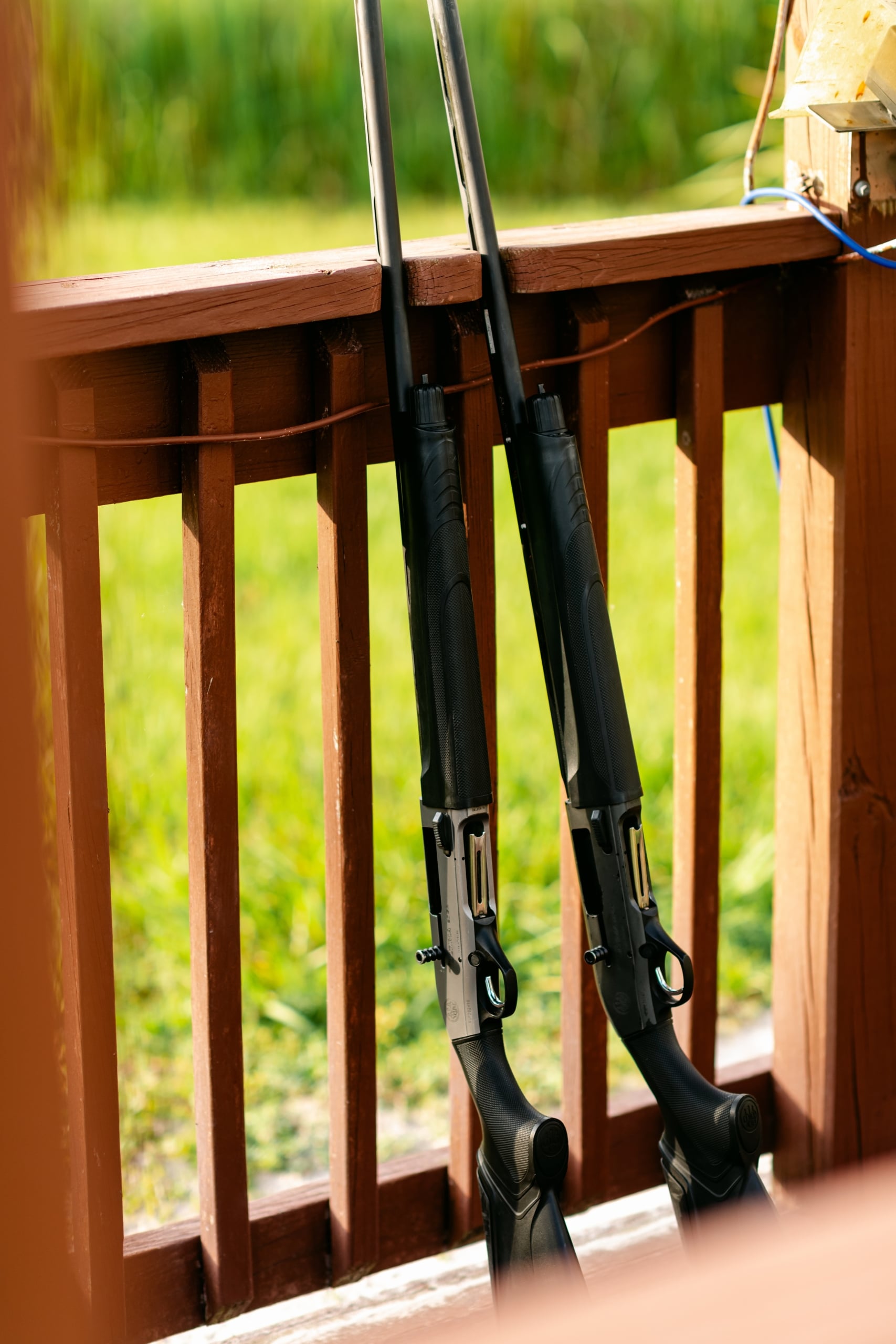 Two sporting rifles leaned against a railing